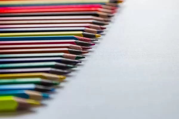 Row of colored pencils on a white background. Detail multicolored pen in line.