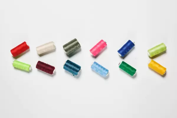 Rows of colorful thread spools on white