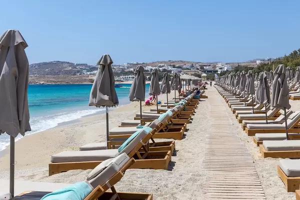 Rows of parasols, emtpy sun beds and a wooden path on the popular Kalafati beach, Mykonos, Greece