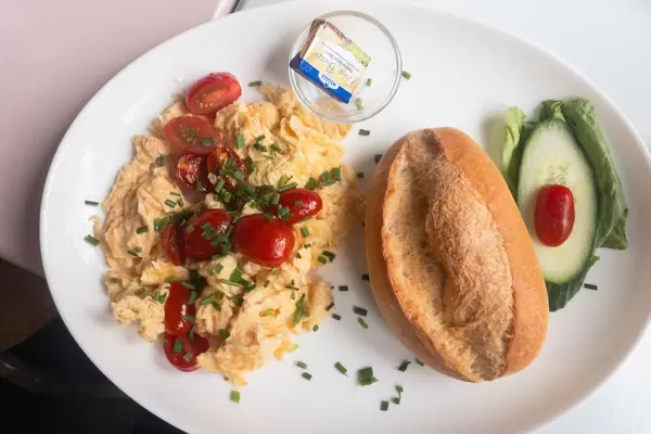 Rührei, Cherrytomaten, Schnittlauch, Brötchen und Butter