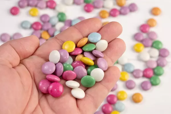 Runde bunte Schokoladen-Süßigkeiten in der Hand über unscharfem Hintergrund