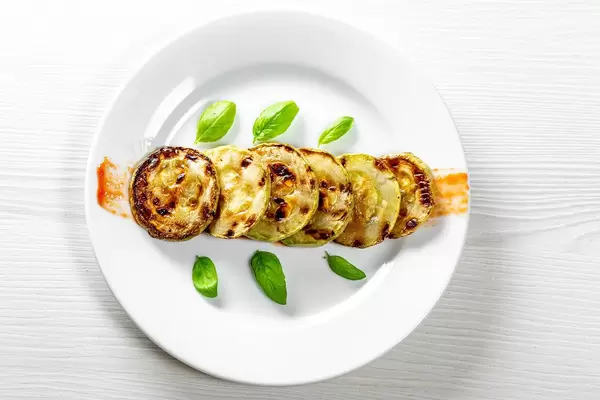 Runde, gegrillte Zucchini mit frischem Basilikum
