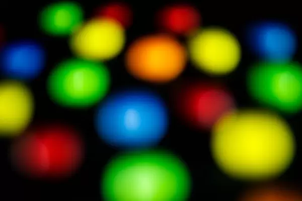 Runde, verschieden farbige Süßigkeiten mit Unschärfe fotografiert auf dunklem Hintergrund