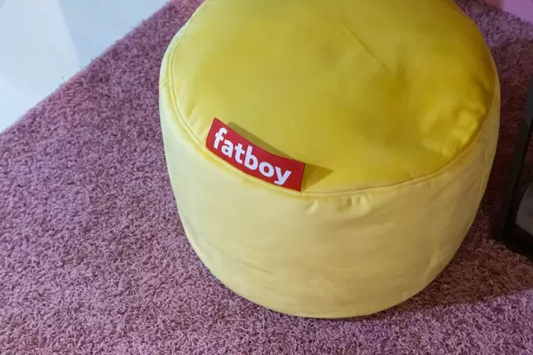 Runder Fatboy Sitzpuff aus gelbem Stoff auf flauschigem Teppich