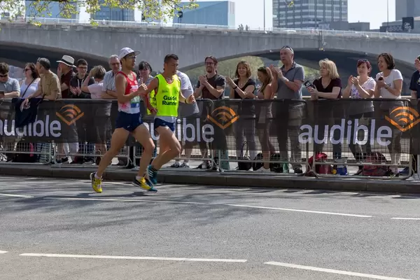 Runners running side by side and holding red rope in hands - London Marathon 2018