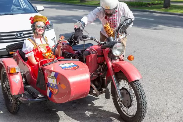 Russisches Pärchen in Tracht gekleidet fährt in einem Motorrad mit Beiwagen