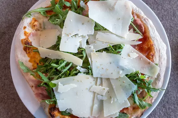 Rustic-style pizza with Parmesan, Rucola and Parma ham