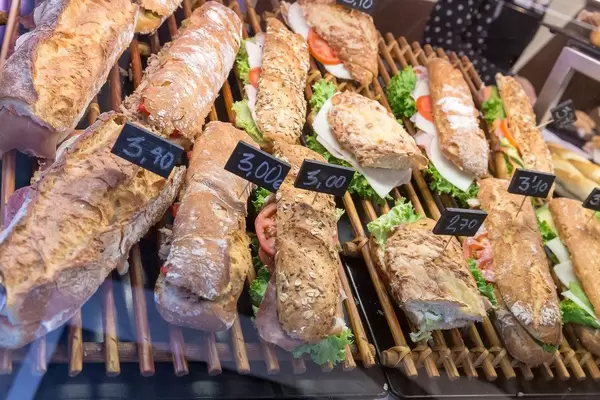 Rustikale Baguettes aus verschiedenen Brotsorten, belegt mit Salat, Wurst, Tomaten und Käse, in Barcelona (Spanien)