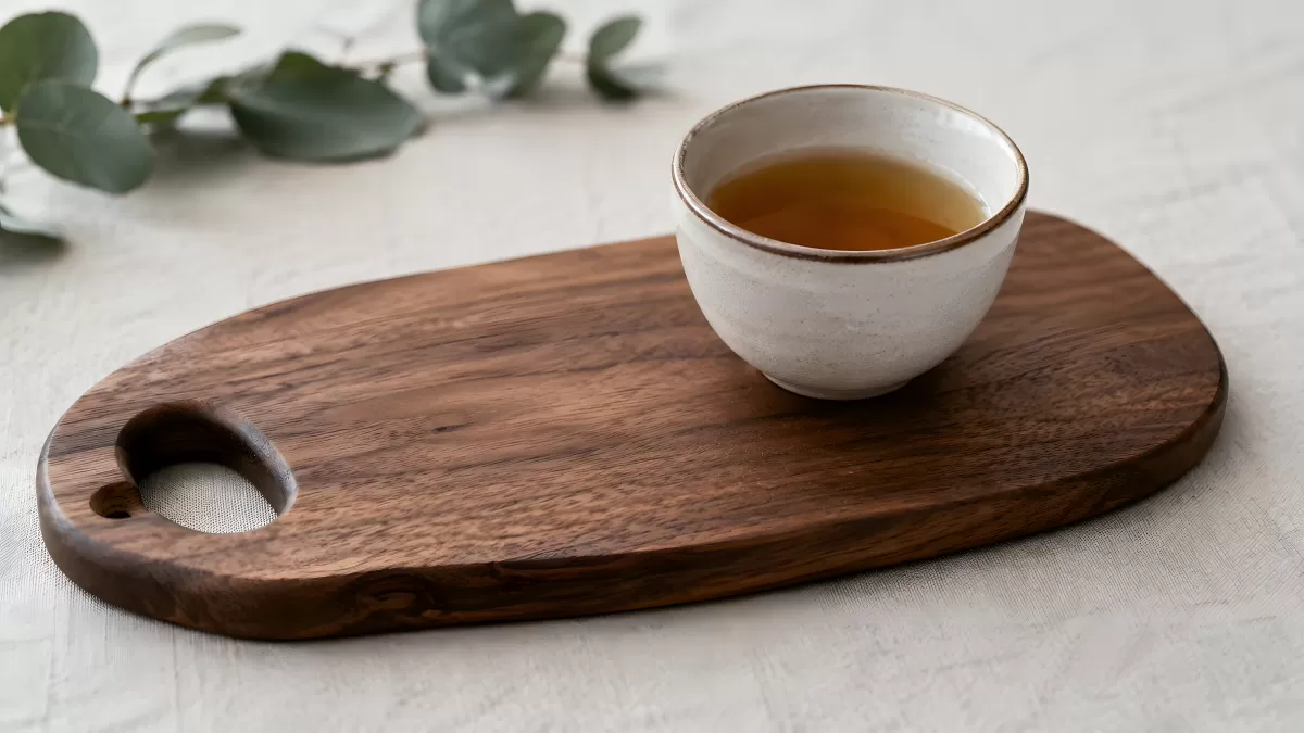 Rustikales Holzbrett mit Keramiktasse und grünem Tee