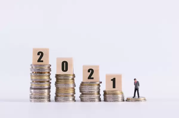 Sad businessman, stack of coins and wooden cubes with 2021 text on white background