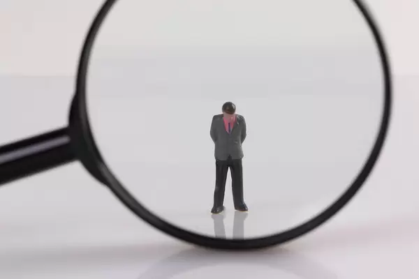 Sad businessman under magnifying glass