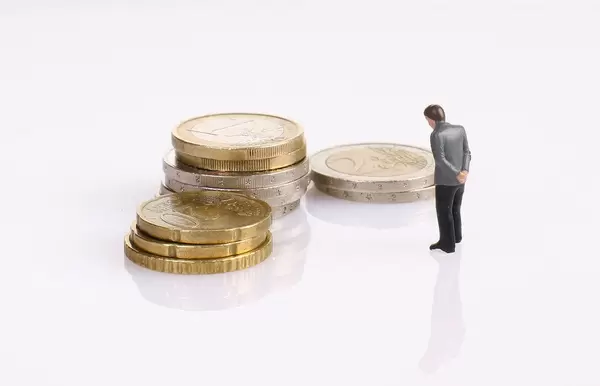 Sad businessman with coin stack on white background