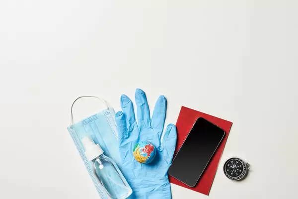 Safe traveling concept - hand sanitizer, face mask, passport and smartphone