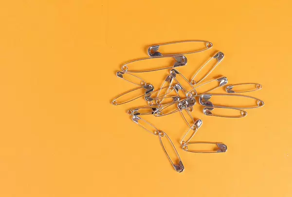 Safety pins on orange background