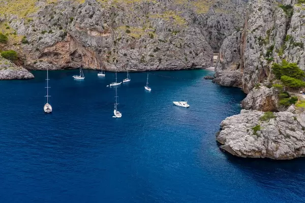 Sailboats and motor boats in front of the steep cliffs of Sa Calobra, northwest coast of Majorca, drone pic