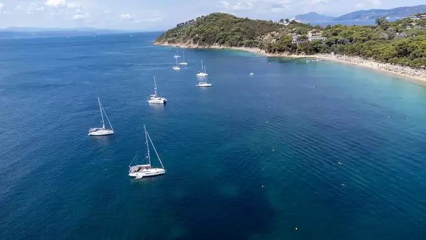 Sailing boats off the coast of Koukounaries, wooded paeninsula and beach on Skiathos