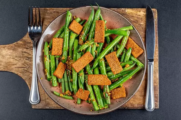 Salad with asparagus and rye rusks with mustard sauce on dark background