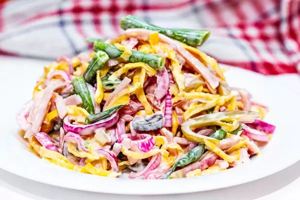 Salad with asparagus, sliced ham and scrambled eggs, pickled purple onion and cucumbers and sauce