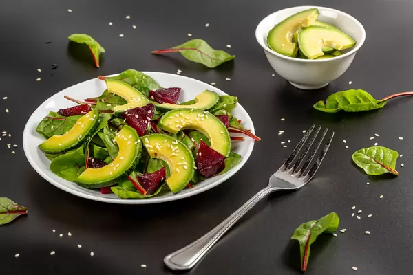 Salad with avocado, beetroot and sesame seeds on a dark background, vegetarian food
