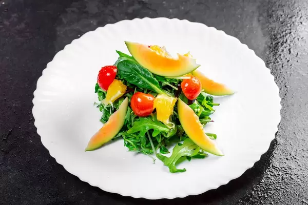 Salad with fresh avocado, cherry tomatoes, orange slices and arugula leaves (Flip 2019)