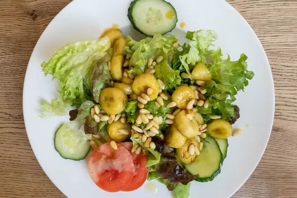 Salad with iceberg lettuce, tomato, cucumber, flambéed banana and pine nuts