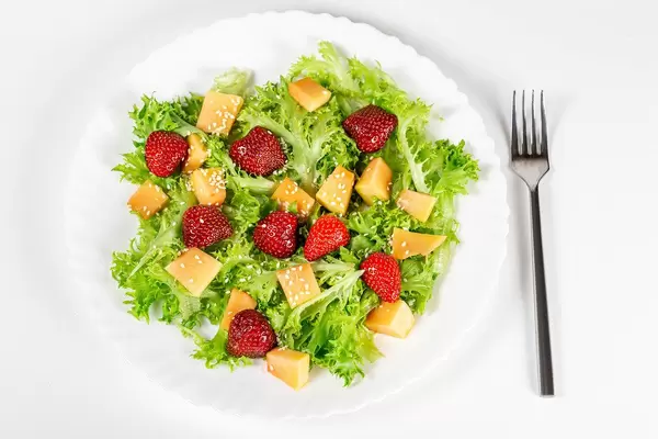 Salad with strawberries, mango, lettuce and sesame seeds. Top view
