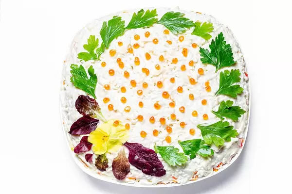 Salad with vegetables and crab sticks, decorated with fresh parsley and spinach leaves with red caviar (Flip 2020)