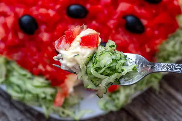 Salad with vegetables, cheese and sauce on a fork closeup