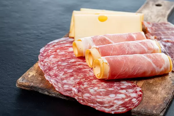 Salami, jamon, ham and cheese sliced on old kitchen wooden Board (Flip 2019)