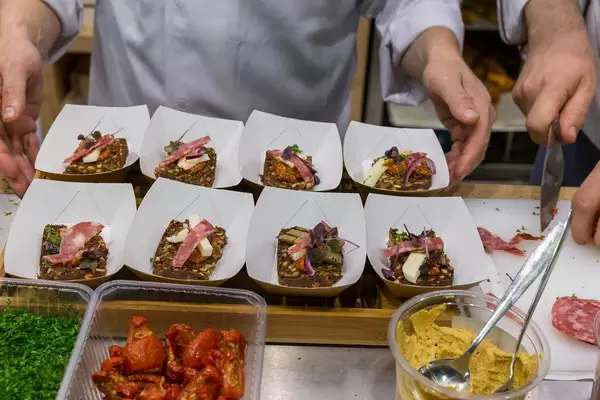Salami, Käse, Aubergine und getrocknete Tomaten auf Vollkornbrot in Pappschüsseln serviert