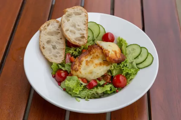 Salat mit Gurken, Cherrytomaten, Haloumi-Käse und zwei Scheiben Brot