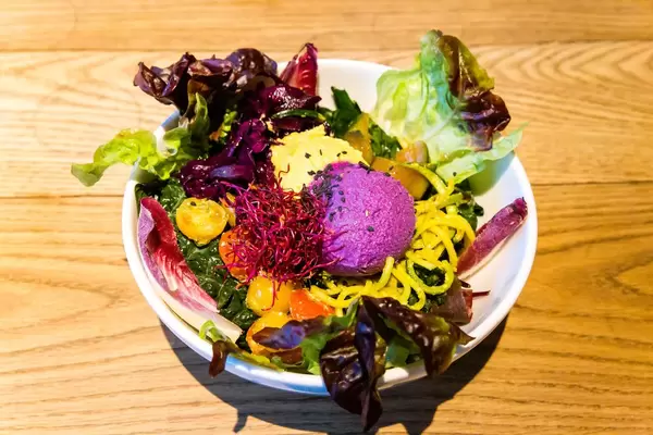 Salatmix, Orangen- und Rotkohl-Hummus, Zucchini-Tagliatelle mit Kurkuma-Pesto, Tomaten, Basilikum im Flex&Kale in Barcelona