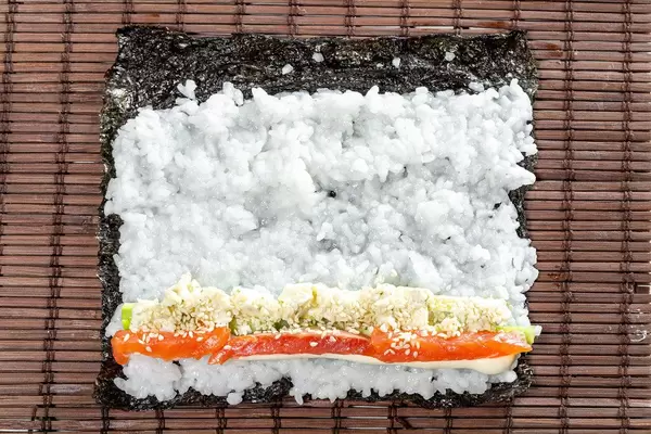 Salmon, avocado, rice on seaweed and cucumber on brown background (Flip 2019)