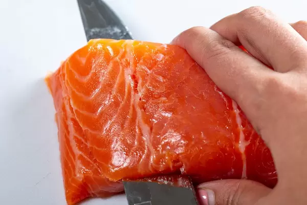Salmon fillet is cut with a knife. Close up (Flip 2019)