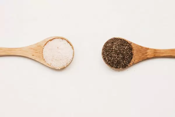 Salzkörner und Pfefferkörner auf Holzbesteck