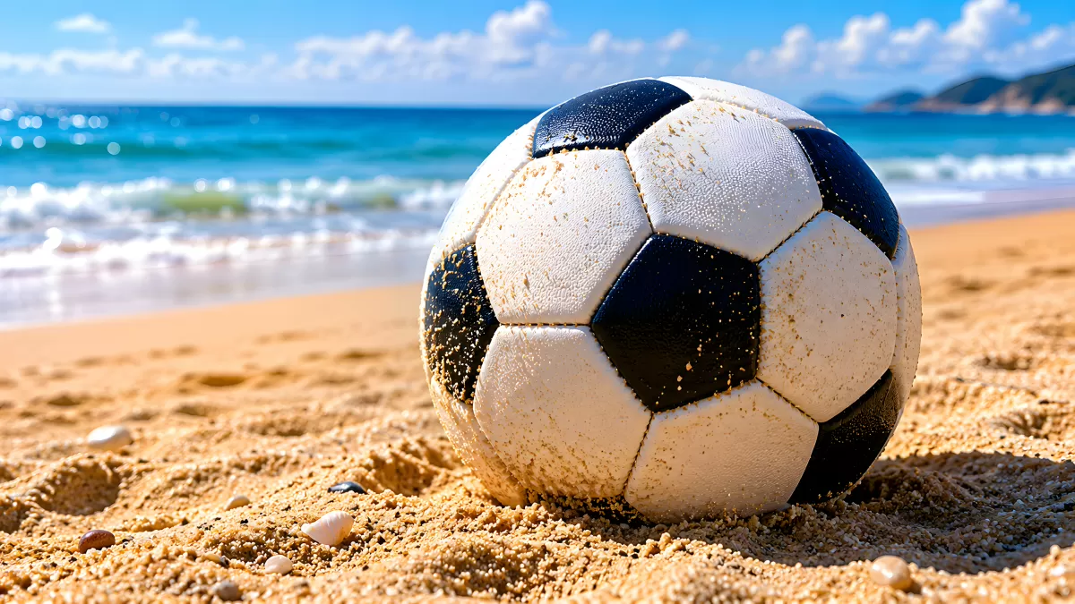 Sandbedeckter Fußball am sonnigen Meeresstrand