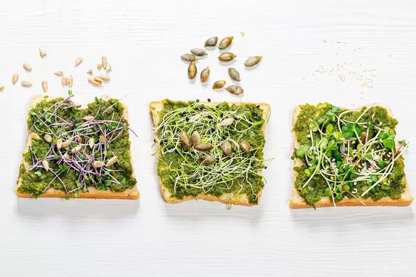 Sandwich mit Kräutern Mikrogrün und Samen auf weißem Holzhintergrund