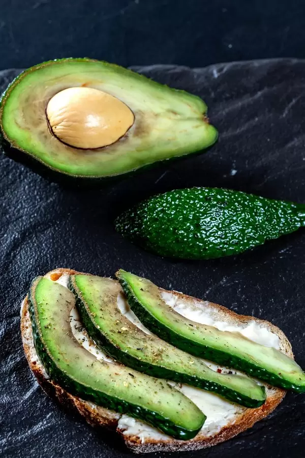 Sandwich on dark rye bread made with fresh sliced avocados