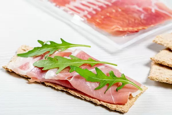 Sandwich with crispbread, dry-cured ham and arugula