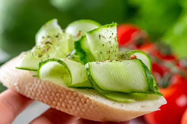 Sandwich with fresh sliced cucumber in hand close-up