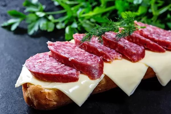 Sandwich with salami and cheese on black background