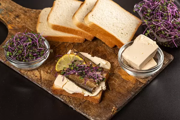 Sandwich with sprats and microgreens on an old wooden board