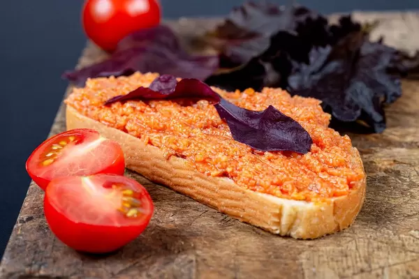 Sandwich with zucchini caviar and purple lettuce leaves on an old kitchen board with fresh tomatoes (Flip 2020)
