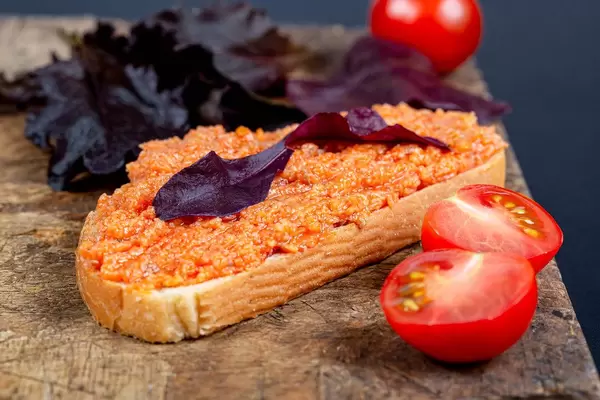 Sandwich with zucchini caviar and purple lettuce leaves on an old kitchen board with fresh tomatoes