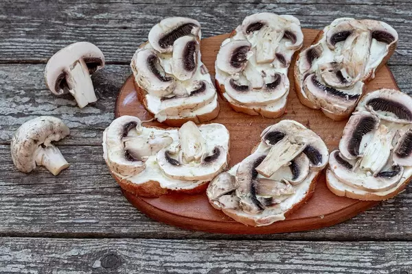 Sandwiches with mushrooms before baking on an old wooden background. The view from the top (Flip 2019)