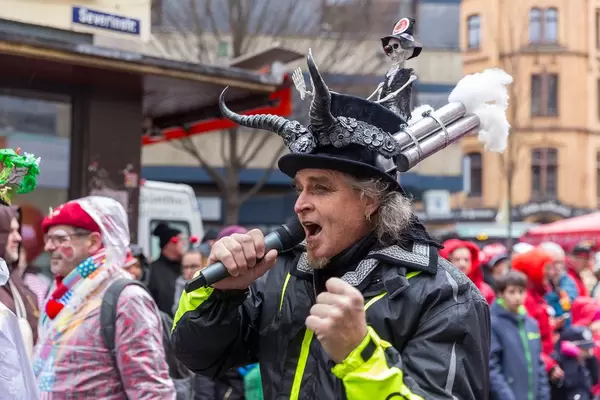 Sänger der Pappnasen-Rotschwarz mit Skelett und Auspuffrohren am Karnevalshut beim Rosenmontagszug in Köln