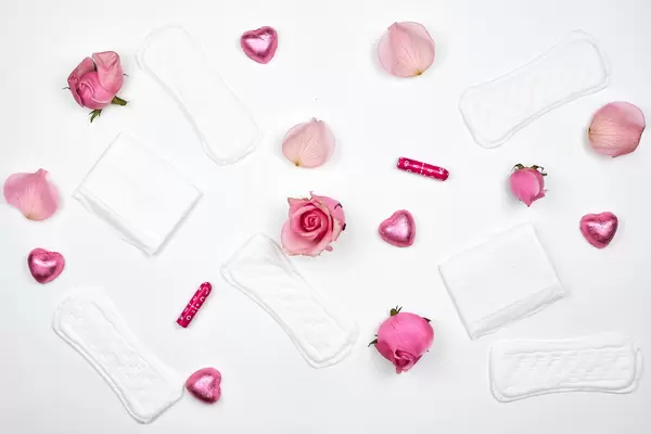 Sanitary pads and tampons with roses on white background