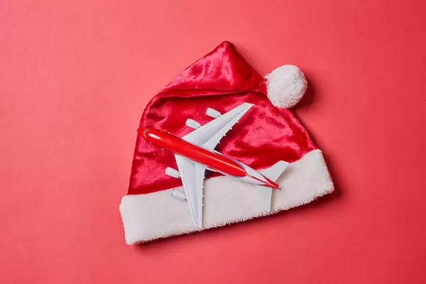 Santa Claus cap and toy airplane on red