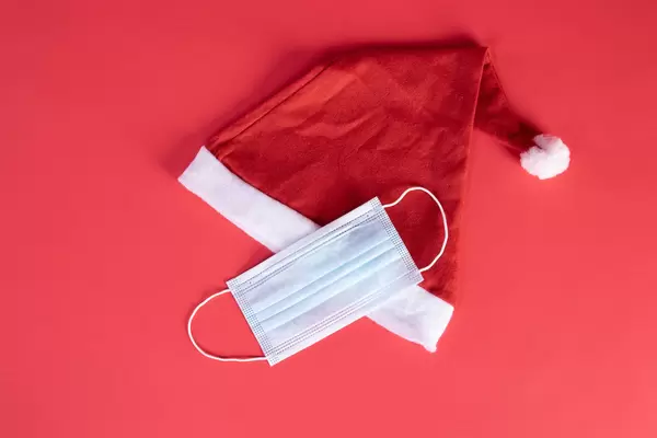 Santa Claus hat and medical face mask on red background