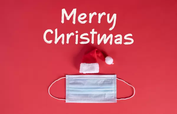 Santa Claus hat with medical face mask and Merry Christmas text on red background